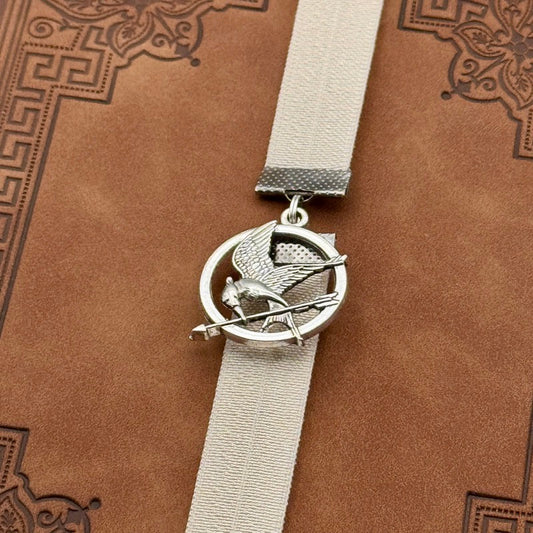 A silver Hunger Games Mockingjay charm on an elastic Bookband