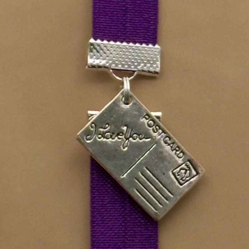 A silver postcard charm on an elastic Bookband